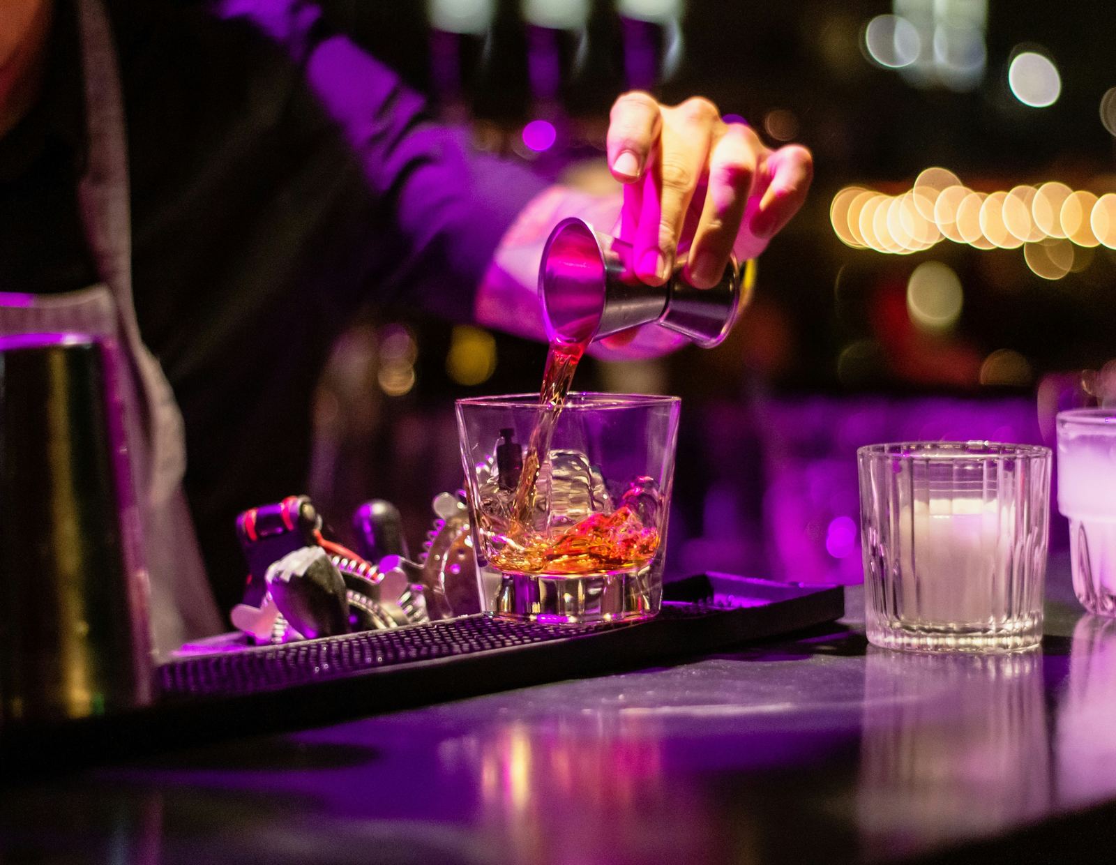 Barkeeper gießt einen Cocktail hinter dem Tresen ein