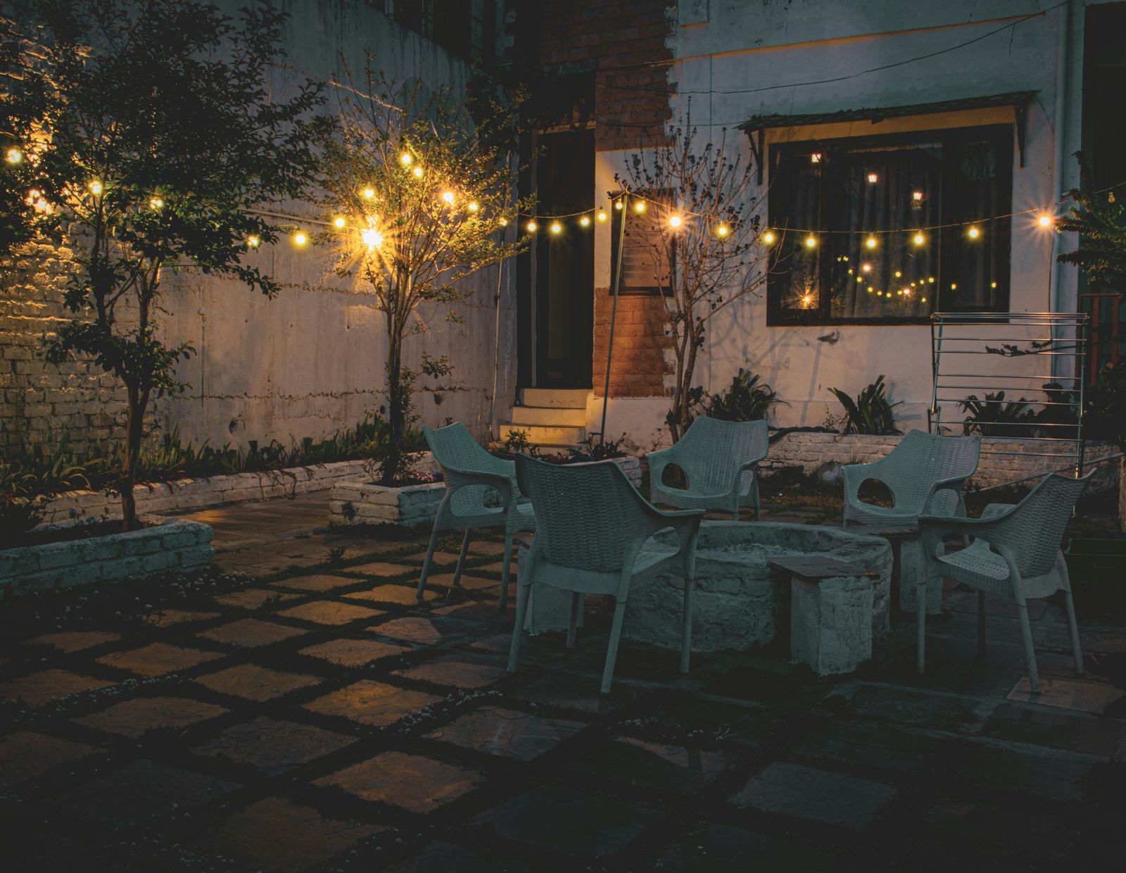 Terrasse mit Tischen, Stühlen und Lichterketten am Abend